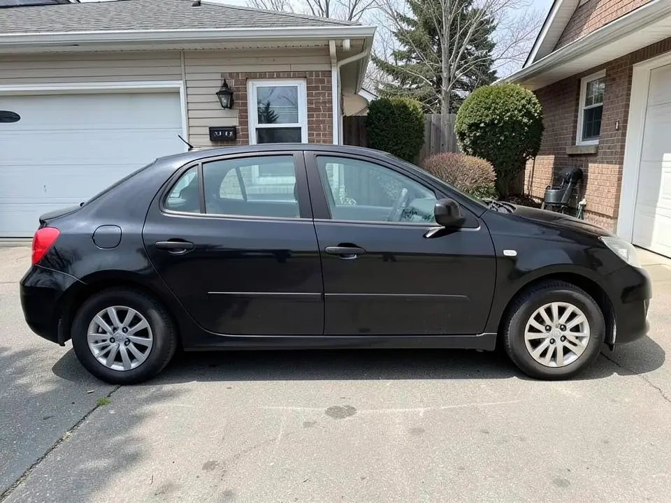 AI-drawn sample: a plain black generic compact car seen from the side, parked in a driveway beside a brick house
