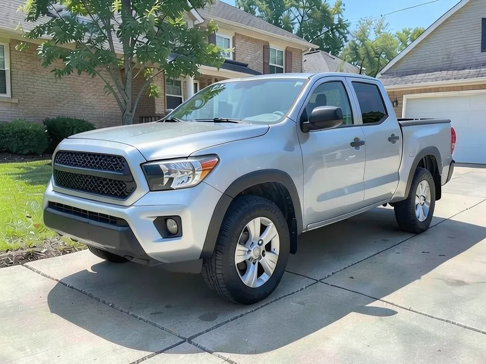 AI-drawn sample: a silver Tacoma-style crew cab pickup on silver factory-style wheels parked on a driveway in front of a brick house